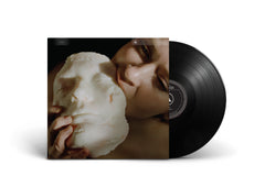 Vinyl record of Devour featuring album cover with a person holding a white sculpture mask close to their face